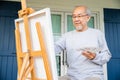 Senior old man painting picture artwork using brush and water color on canvas