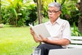 Senior old man reading a book in the park and drinking water. Concept of retirement lifestyle and hobby Royalty Free Stock Photo