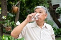 senior old man reading a book in the park and drinking water. Concept of retirement lifestyle and hobby Royalty Free Stock Photo