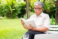 Senior old man reading a book in the park and drinking water. Concept of retirement lifestyle and hobby Royalty Free Stock Photo