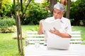 Senior old man reading a book in the park and drinking water. Concept of retirement lifestyle and hobby Royalty Free Stock Photo