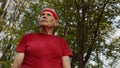 Senior old man runner in city park listening music, enjoying healthy active lifestyle