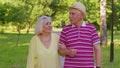 Senior old stylish tourists couple grandmother, grandfather having a walk and talking in summer park Royalty Free Stock Photo