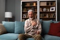 Senior older man getting chest pain in living room, heart attack holding his hand on the chest sitting on sofa at home. Health Royalty Free Stock Photo