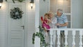 Senior ouple sitting with granddaughter in porch at home. Using mobile phone for online video call