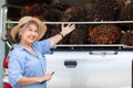 Senior owner Asia woman showing the bunch of red palm seed on car truck