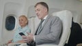 Senior passenger man using smartphone on airplane while traveling for safe flight Royalty Free Stock Photo