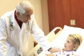 Senior Pediatrician Examining Girl In Clinic