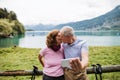 Senior pensioner couple hikers standing in nature, taking selfie when kissing.