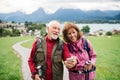 Senior pensioner couple with hiking in nature, using smartphone.
