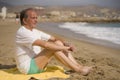 Senior pensioner sitting relaxed on the beach - retired old man on his 70s looking at the sea thoughtful and contemplative in