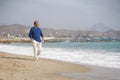 Senior pensioner taking a walk relaxed on the beach - retired old man on his 70s looking at the sea thoughtful and contemplative