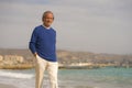 Senior pensioner walking relaxed on the beach - retired old man on his 70s looking at the sea thoughtful and contemplative in