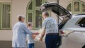 Senior people with granddaughter putting voyage baggage and trolleys inside vehicle Royalty Free Stock Photo