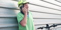 Senior people grandfather talking at the cellphone close to his e bike. Healthy lifestyle for retired person. Yellow helmet. Metal