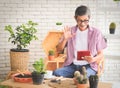 Senior people lifestyle and technology  concept.  Asian elderly man sitting at table with houseplants and gardening tools , making Royalty Free Stock Photo