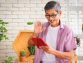 Senior people lifestyle and technology  concept. Close up image of happy Asian elderly man sitting at table with houseplants and Royalty Free Stock Photo