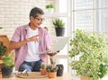 Senior people lifestyle and technology  concept. Happy Asian elderly man sitting at table with houseplants and gardening tools , Royalty Free Stock Photo