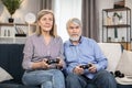 Senior people playing video games with controllers indoors Royalty Free Stock Photo