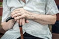 Senior person sitting on wooden bench outdoors. Old man hands holding walking stick. Poverty, loneliness and Royalty Free Stock Photo