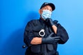 Senior police man wearing surgical mask serious face thinking about question with hand on chin, thoughtful about confusing idea