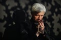 Senior priest holding rosary and praying in serene lighting