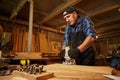 Senior Professional carpenter in uniform working of manual milling machine in the carpentry workshop Royalty Free Stock Photo