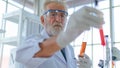 Senior professor male researcher tests a chemical liquid tube with face concentration about lab testing science. with interior whi