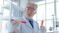 Senior professor male researcher tests a chemical liquid tube with face concentration about lab testing science. with interior whi