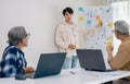 senior programmer bootcamlp,Asian young instructor guides senior learners through a programming on whiteboard, highlighting Royalty Free Stock Photo