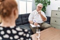 Senior psychologist man at consultation office looking confident at the camera smiling with crossed arms and hand raised on chin Royalty Free Stock Photo