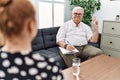 Senior psychologist man at consultation office smiling looking to the camera showing fingers doing victory sign Royalty Free Stock Photo