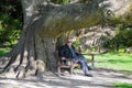 Senior relaxing under giant trunk of a tree Royalty Free Stock Photo