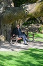 Senior relaxing under giant trunk of a tree Royalty Free Stock Photo