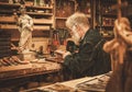 Senior restorer working with antique decor element in his workshop Royalty Free Stock Photo