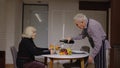 Senior retired couple having fun drinking wine and eating meal during romantic supper in kitchen