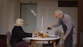 Senior retired couple having fun drinking wine and eating meal during romantic supper in kitchen