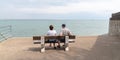 Senior retired couple looking sea sit on bench on vendee beach France in web banner template