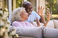 Senior Retired Couple Sitting Outside In Garden At Home Making Video Call On Mobile Phone Royalty Free Stock Photo