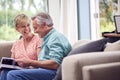 Senior Retired Couple Sitting On Sofa At Home Enjoying Looking Through Family Photo Album Royalty Free Stock Photo