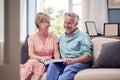 Senior Retired Couple Sitting On Sofa At Home Enjoying Looking Through Family Photo Album Royalty Free Stock Photo