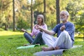 Senior retired family couple man and woman in lotus pose meditating in park sitting on sports mat with eyes closed Royalty Free Stock Photo