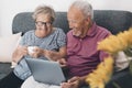 Senior retired happy couple embracing using laptop together, smiling elderly family reading news, shopping online at home, older Royalty Free Stock Photo