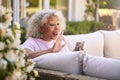 Senior Retired Woman Sitting Outside In Garden At Home Making Video Call On Mobile Phone Royalty Free Stock Photo