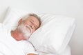 Senior retirement man sleeping happily in his white blanket bed Royalty Free Stock Photo