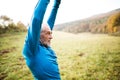 Senior runner with earphones doing stretching. Autumn nature. Royalty Free Stock Photo