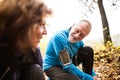 Senior runners in nature, tying shoelaces. Man with smartphone.