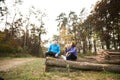 Senior runners sitting on wooden logs, resting, drinking water.