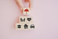 hand put wooden cube block screen umbrella icon on top of family, heart, graduationhat, house and car symbol for