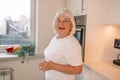 Senior 60s woman drinking pure water from glass in kitchen. Space for text Royalty Free Stock Photo